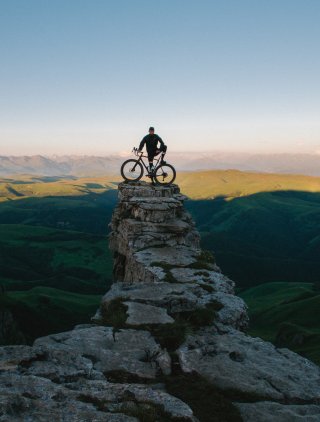 Man with a bicycle on a cliff